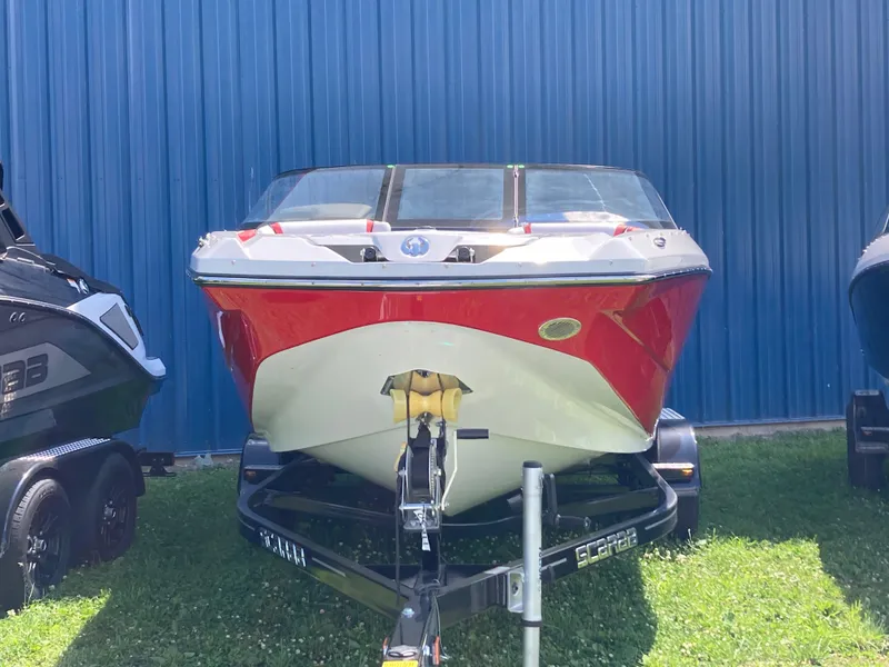 Slide: The Image of 2024 Scarab 215 boat on trailer, red and white, parked on grass. - 2