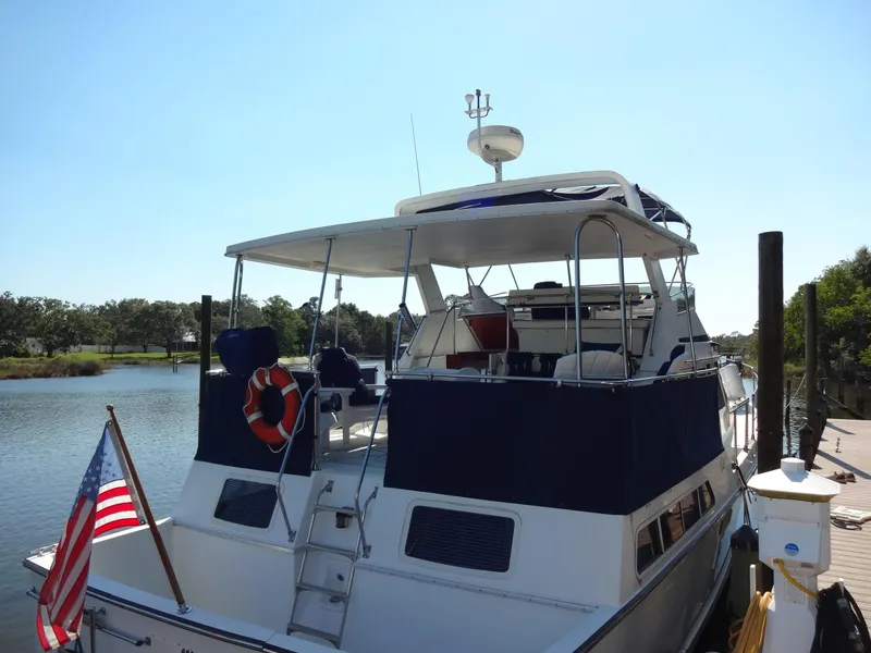 Slide: The Image of 1986 Tollycraft 44 CPMY yacht docked by a serene river. - 14
