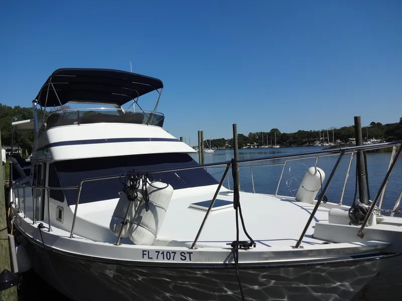 Slide: The Image of 1986 Tollycraft 44 CPMY yacht docked by a serene waterfront. - 15