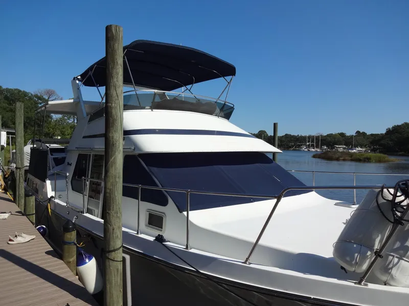 Slide: The Image of 1986 Tollycraft 44 CPMY yacht docked by a serene river. - 16