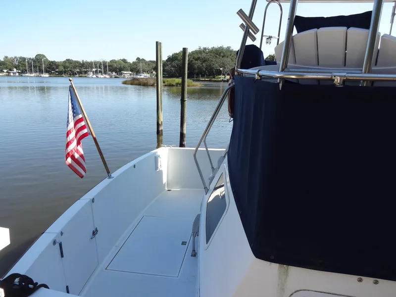 Slide: The Image of 1986 Tollycraft 44 CPMY yacht docked by serene waters with American flag. - 19