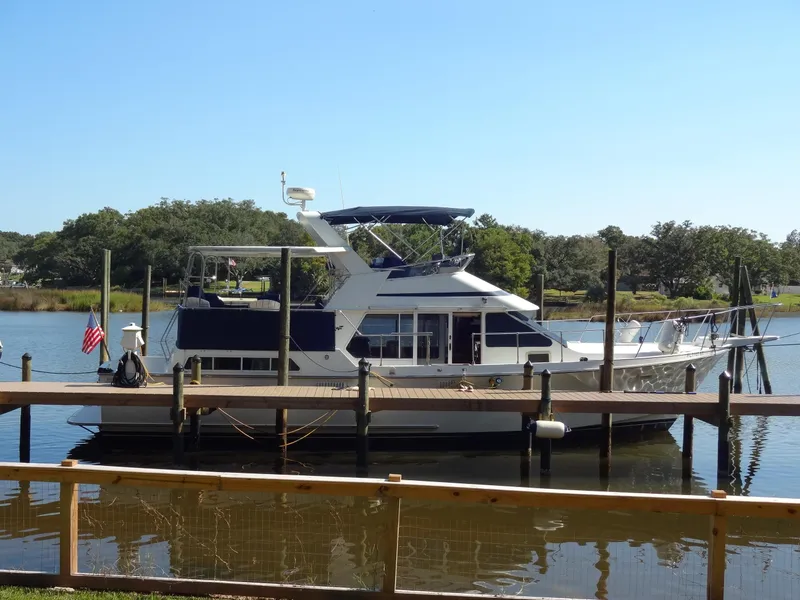 Slide: The Image of 1986 Tollycraft 44 CPMY yacht docked on a serene river. - 2