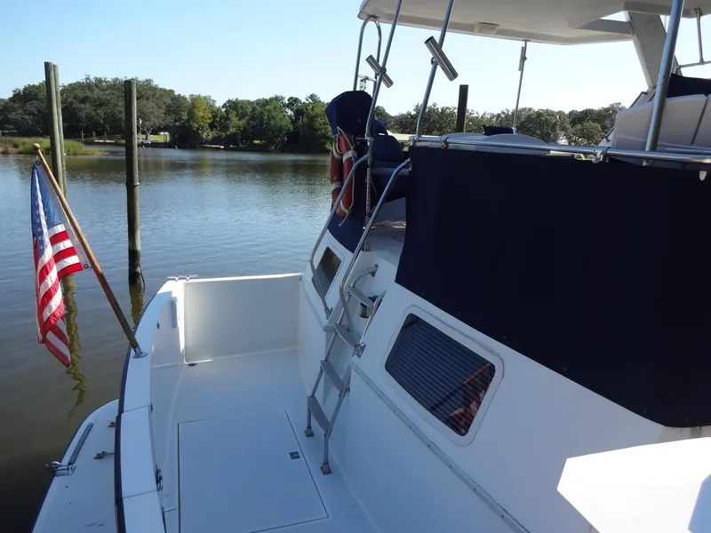 Slide: The Image of 1986 Tollycraft 44 CPMY yacht docked by a serene lake with American flag. - 20