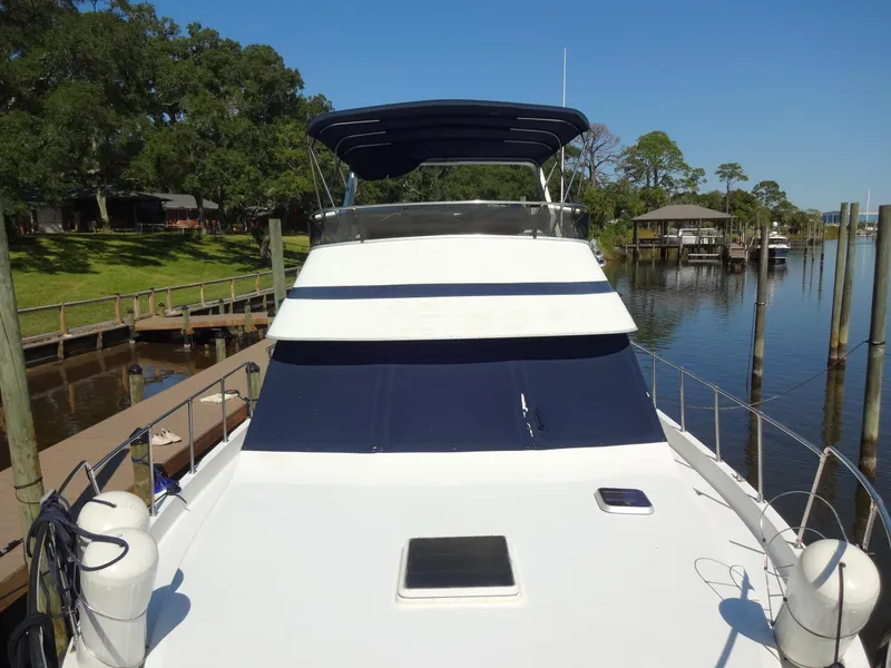 Slide: The Image of 1986 Tollycraft 44 CPMY yacht docked by a serene waterfront. - 23