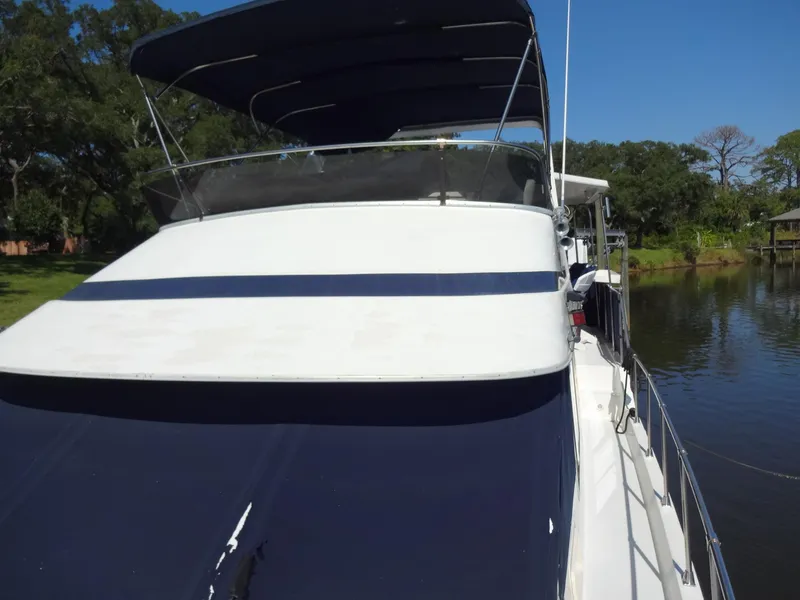 Slide: The Image of 1986 Tollycraft 44 CPMY yacht with blue canopy on a serene river. - 24