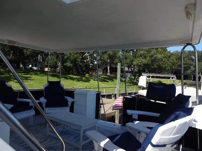 Slide: The Image of 1986 Tollycraft 44 CPMY yacht deck with seating, docked near lush greenery. - 25