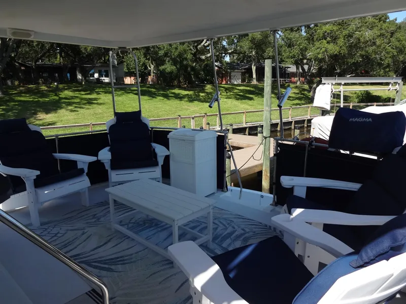 Slide: The Image of 1986 Tollycraft 44 CPMY yacht deck with seating and table, docked near lush greenery. - 26