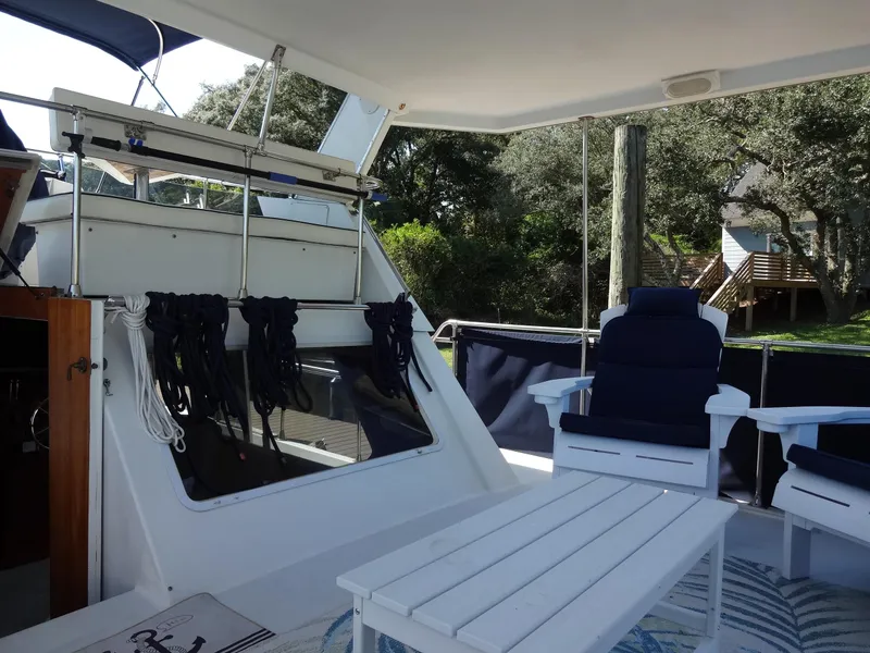 Slide: The Image of 1986 Tollycraft 44 CPMY yacht deck with seating and table, surrounded by lush greenery. - 30