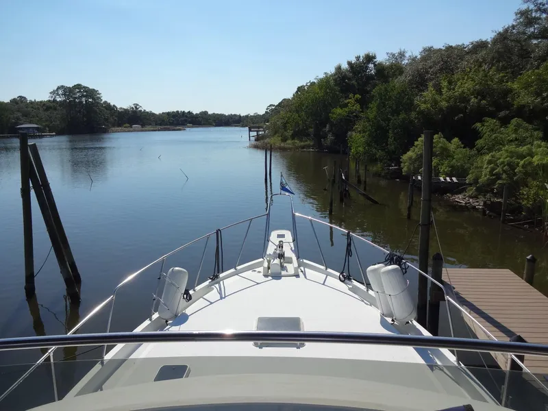 Slide: The Image of 1986 Tollycraft 44 CPMY yacht on a serene river with lush greenery. - 35