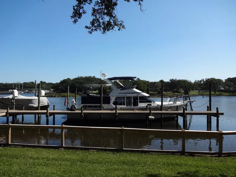 Slide: The Image of 1986 Tollycraft 44 CPMY yacht docked on a serene lake under clear blue skies. - 4