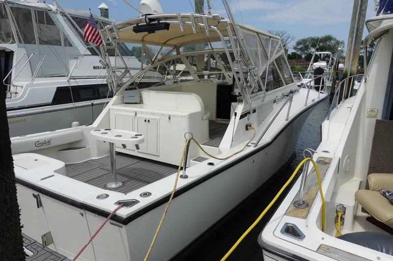 Slide: The Image of 2002 Carolina Classic 35 boat docked at marina, featuring spacious deck and canopy. - 1