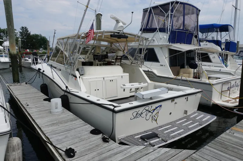 Slide: The Image of 2002 Carolina Classic 35 boat docked at marina, featuring spacious deck and American flag. - 10