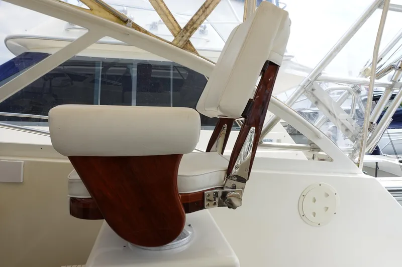 Slide: The Image of Captain's chair on a 2002 Carolina Classic 35 boat, featuring white cushions and wooden accents. - 24
