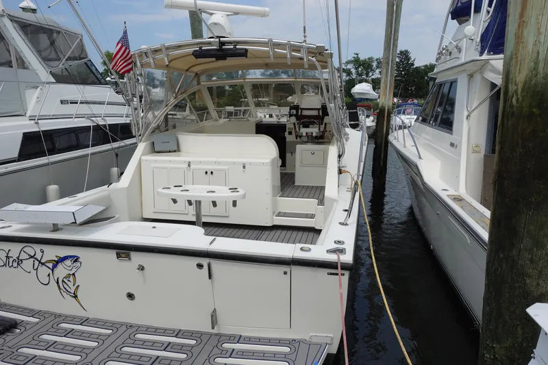 Slide: The Image of 2002 Carolina Classic 35 boat docked, featuring spacious deck and fishing equipment. - 5