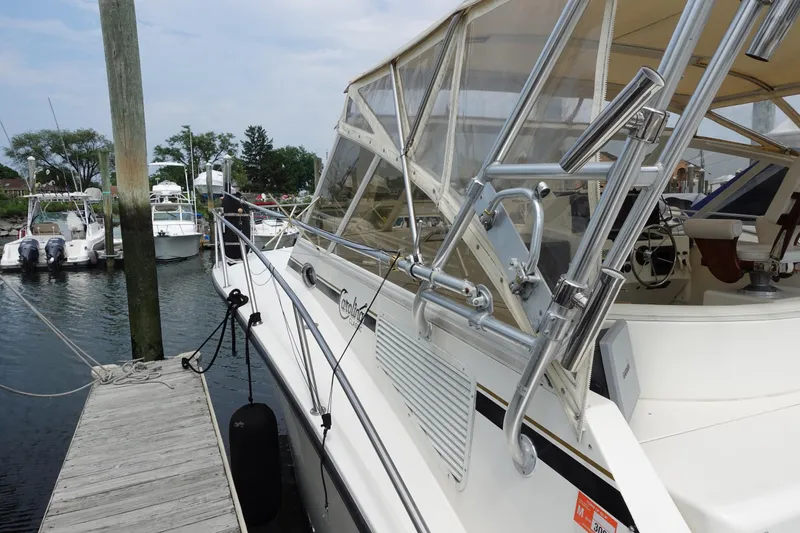 Slide: The Image of 2002 Carolina Classic 35 boat docked at marina with clear canopy and polished metal rails. - 8