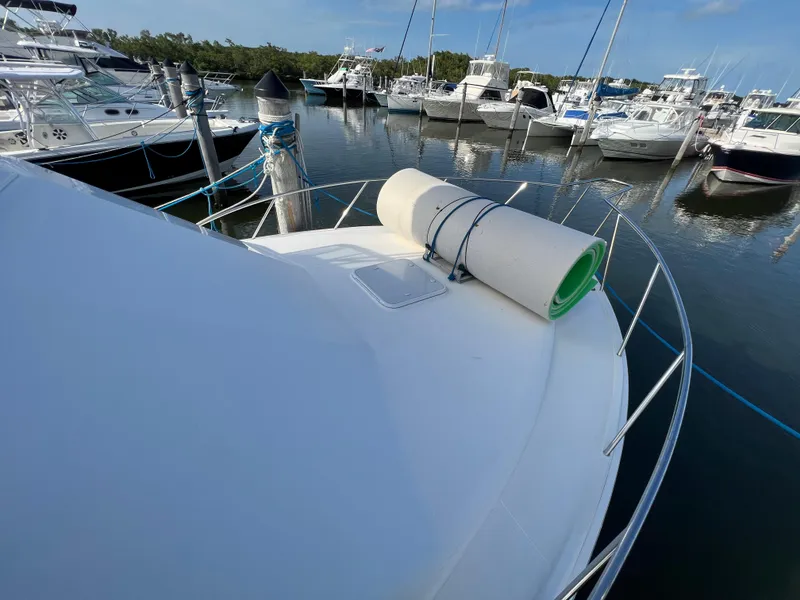 Slide: The Image of 2000 Cabo 35 Flybridge Sportfisher docked at marina with rolled-up mat on bow. - 13