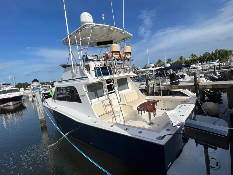 Slide: The Image of 2000 Cabo 35 Flybridge Sportfisher docked at marina under clear sky. - 2