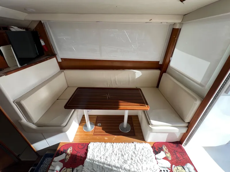 Slide: The Image of Cabo 35 Flybridge Sportfisher 2000 interior dining area with white seating and wooden table. - 37