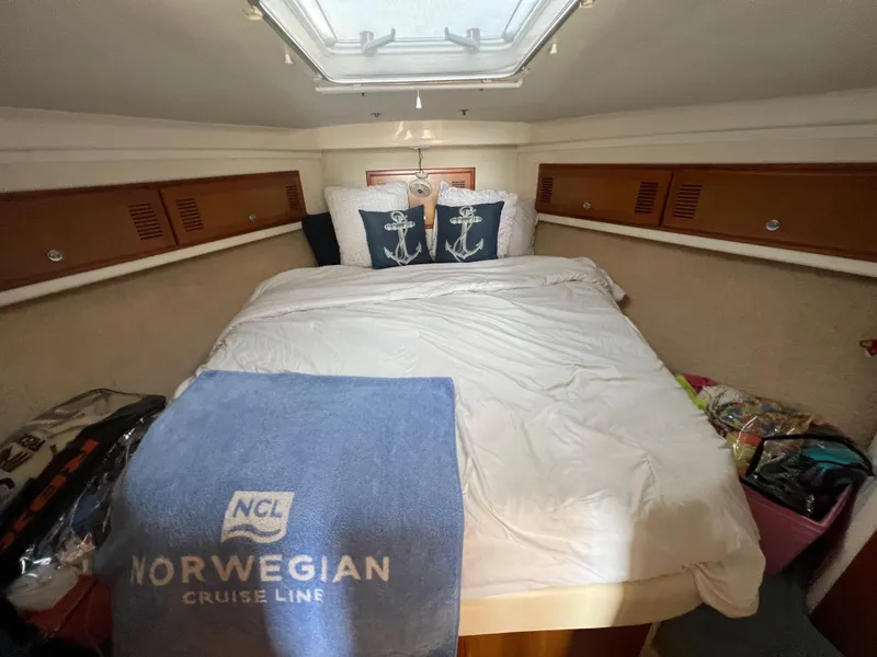 Slide: The Image of Cabo 35 Flybridge Sportfisher 2000 cabin with bed, pillows, and Norwegian Cruise Line towel. - 44