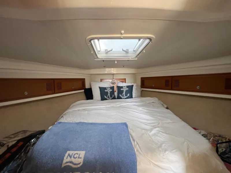 Slide: The Image of Cabo 35 Flybridge Sportfisher 2000 cabin with bed, anchor-themed pillows, and skylight. - 45