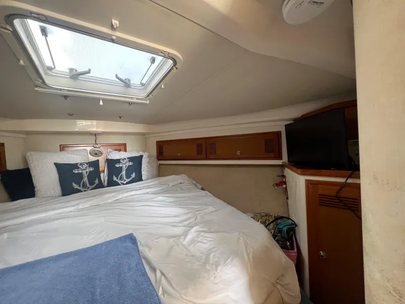 Slide: The Image of Cabo 35 Flybridge Sportfisher 2000 cabin interior with bed, pillows, and TV. - 46