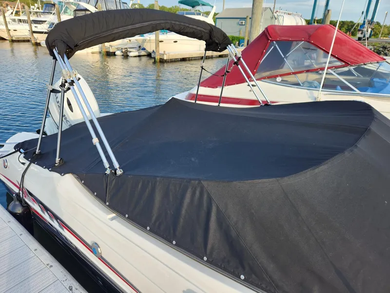 Slide: The Image of 2022 Stingray 231 DC boat with black cover docked at marina. - 2