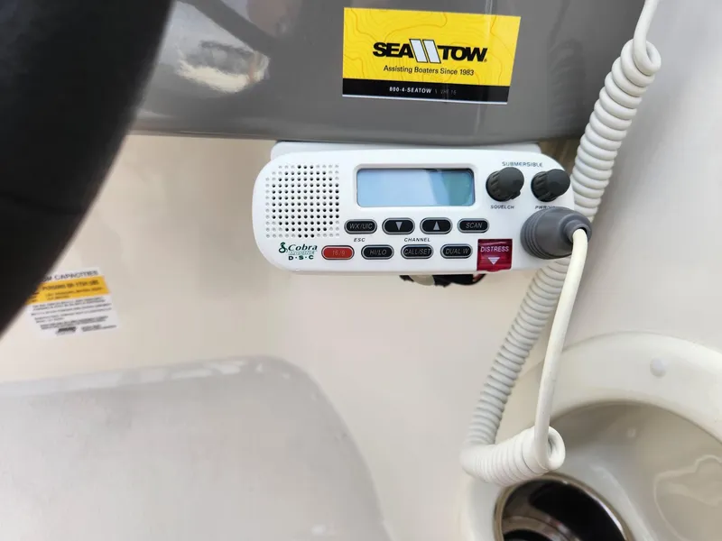 Slide: The Image of VHF radio on 2022 Stingray 231 DC boat dashboard with Sea Tow sticker. - 20
