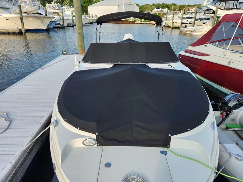 Slide: The Image of 2022 Stingray 231 DC boat docked, covered, with surrounding marina view. - 4