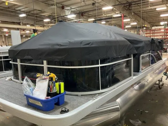 Slide: The Image of 2025 Bennington 20 SVL pontoon boat under cover in a factory setting. - 18