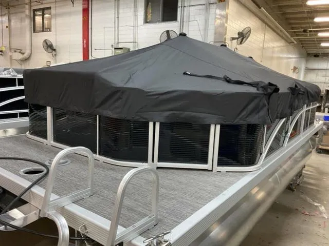 Slide: The Image of 2025 Bennington 20 SVL pontoon boat with black cover in a warehouse setting. - 19