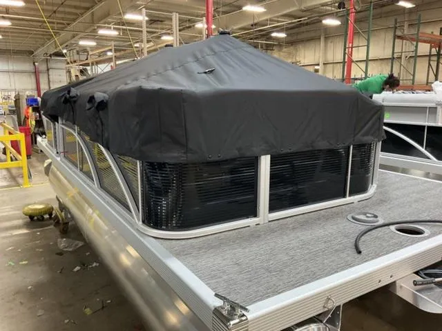 Slide: The Image of 2025 Bennington 20 SVL pontoon boat with black cover in a factory setting. - 20