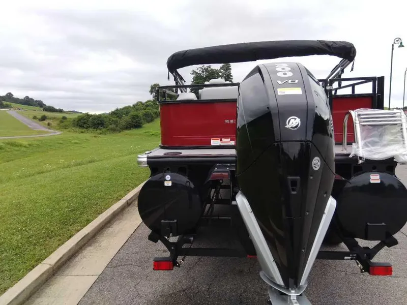 Slide: The Image of 2024 Regency 250 DL3 pontoon boat with powerful outboard motor, parked on a scenic road. - 2