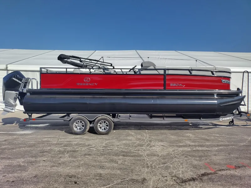 Slide: The Image of 2024 Regency 250 DL3 pontoon boat with red and black exterior on a trailer. - 2