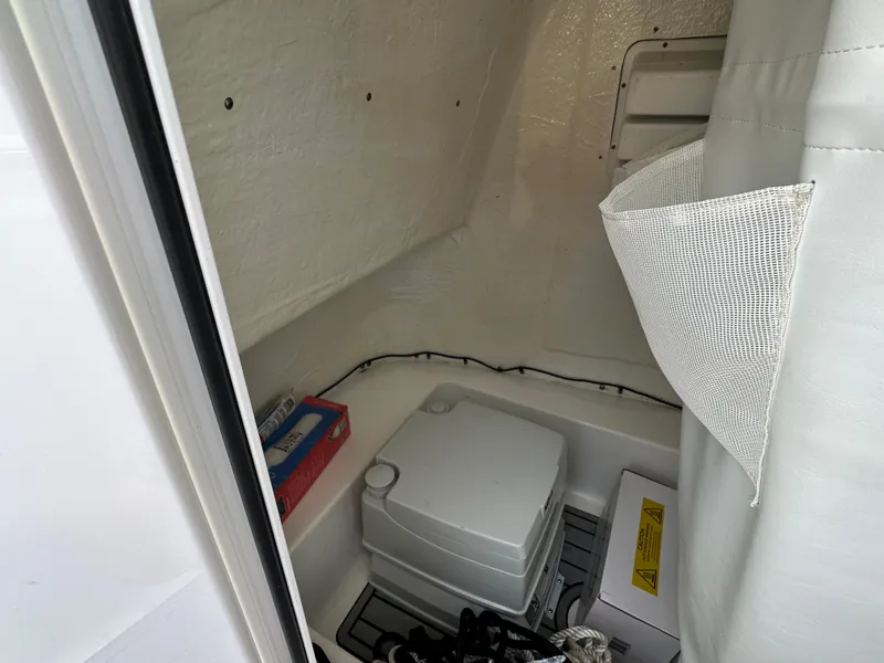 Slide: The Image of 2022 Tidewater 198 CC boat interior storage compartment with portable toilet and supplies. - 20