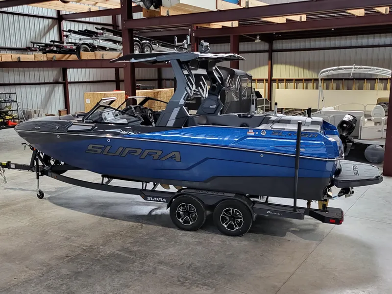 Slide: The Image of 2024 Supra SL boat in a warehouse, blue exterior, on a trailer. - 19