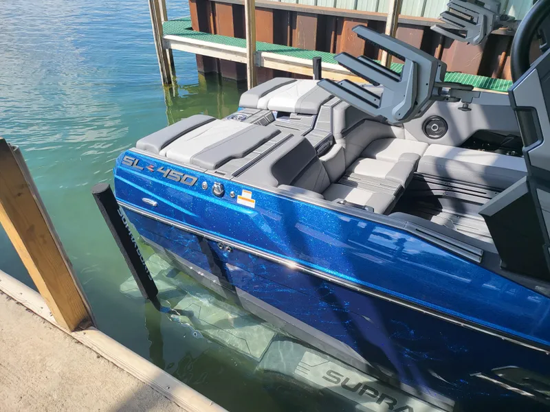 Slide: The Image of 2024 Supra SL boat docked, featuring sleek blue design and comfortable seating. - 21