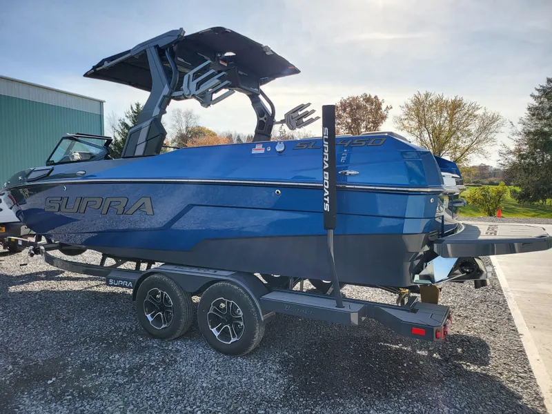 Slide: The Image of 2024 Supra SL boat in blue on a trailer, parked outdoors. - 31