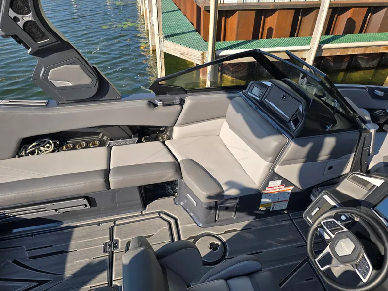 Slide: The Image of 2024 Supra SL boat interior with sleek seating and modern dashboard near dock. - 37