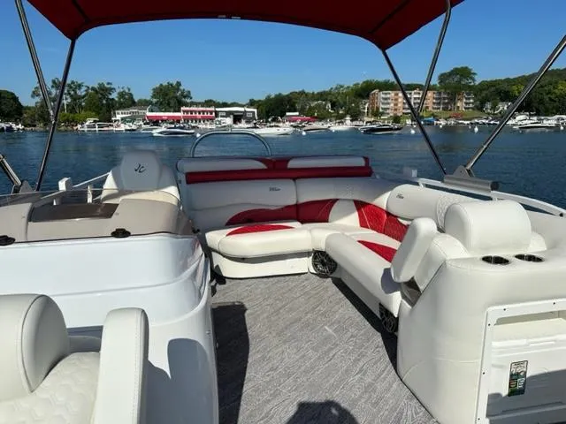 Slide: The Image of 2023 JC SportToon 24 TT pontoon boat with red and white seating on a lake. - 17