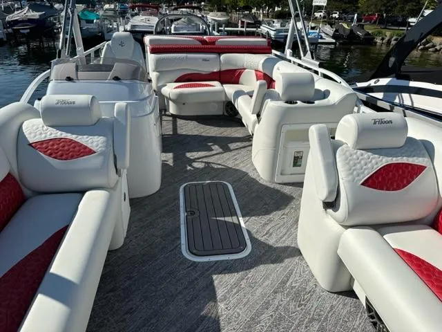 Slide: The Image of 2023 JC SportToon 24 TT pontoon boat with red and white seating, docked at marina. - 23