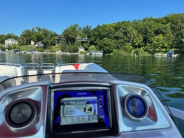 Slide: The Image of 2023 JC SportToon 24 TT boat dashboard on a scenic lake with lush greenery. - 8