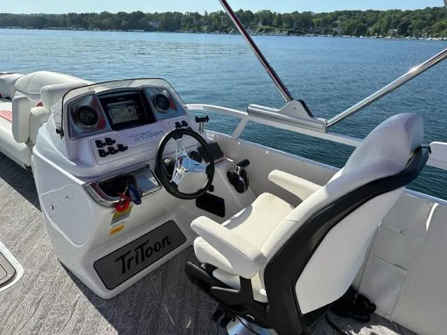 Slide: The Image of 2023 JC SportToon 24 TT boat cockpit with steering wheel and control panel on a lake. - 5