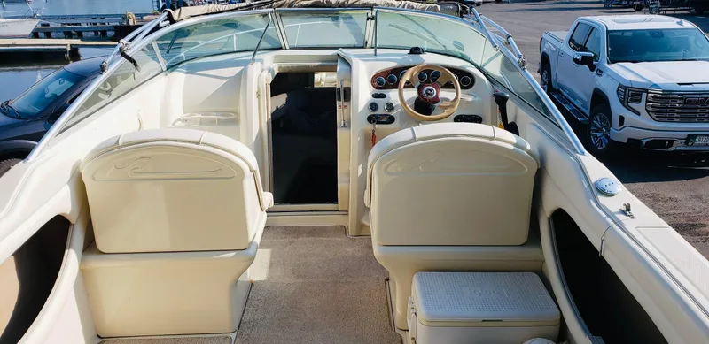 Slide: The Image of 2001 Sea Ray 225 Weekender boat interior with steering wheel and seating, docked near a truck. - 3