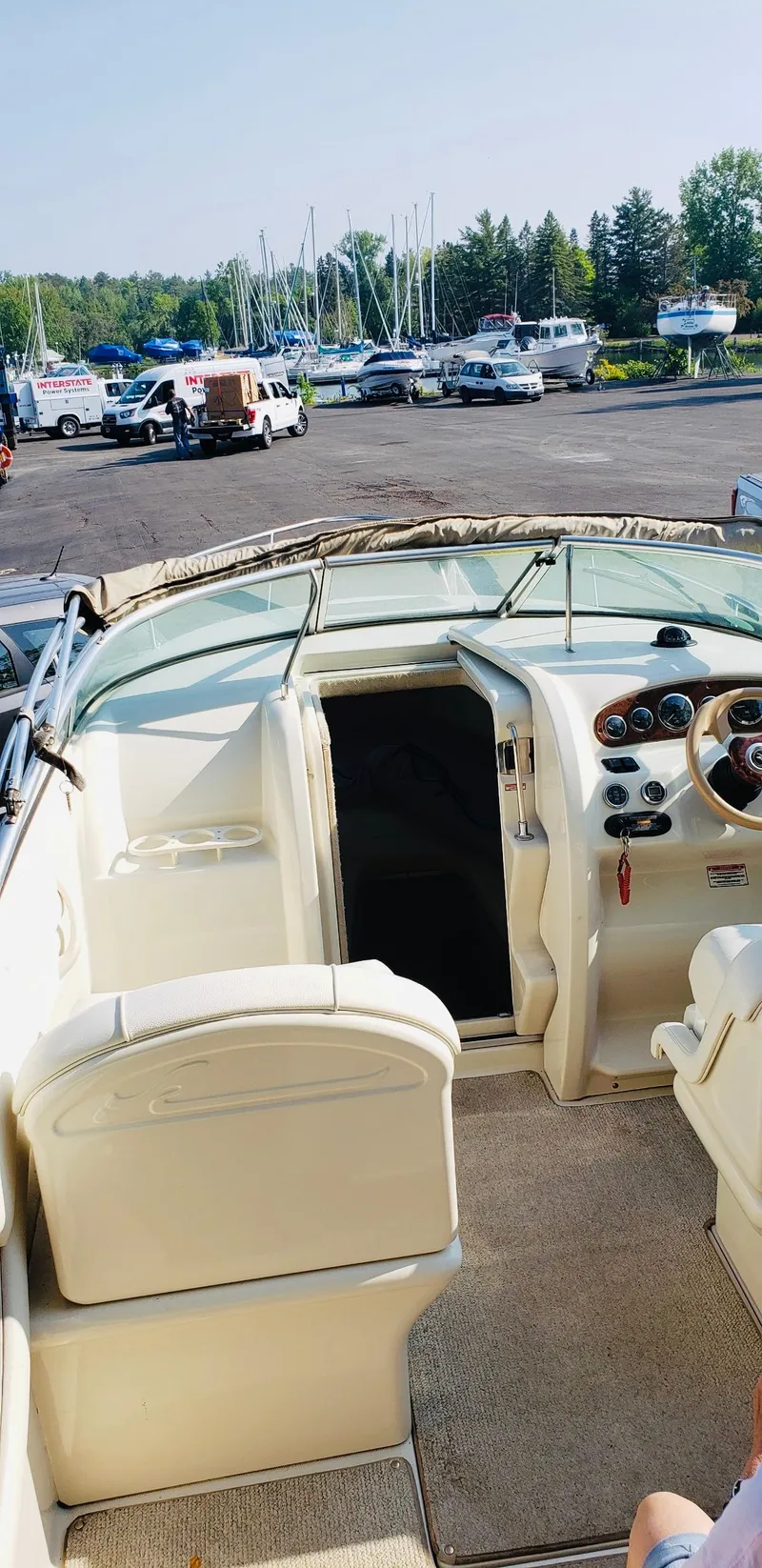Slide: The Image of 2001 Sea Ray 225 Weekender boat interior with dashboard and seating, parked near marina. - 6