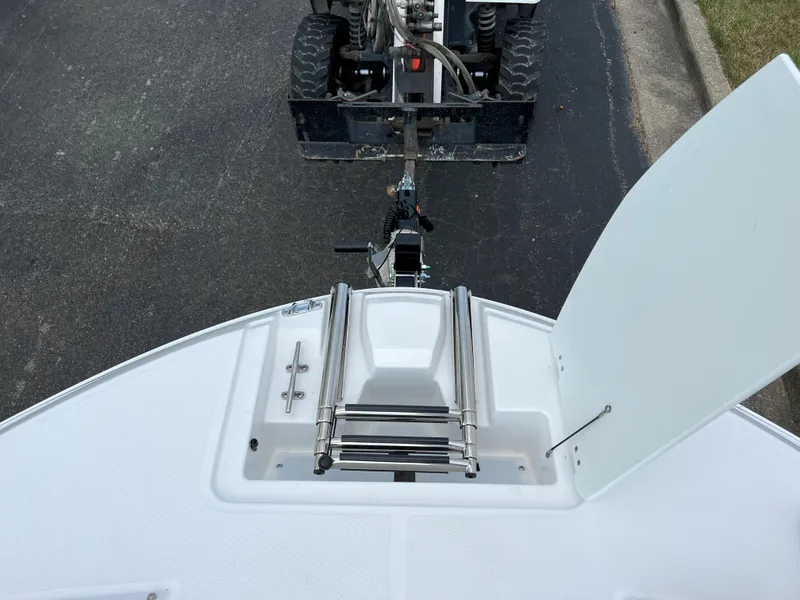 Slide: The Image of 2024 Hurricane SunDeck Sport 205 IO boat being towed, showing bow ladder and storage compartment. - 12