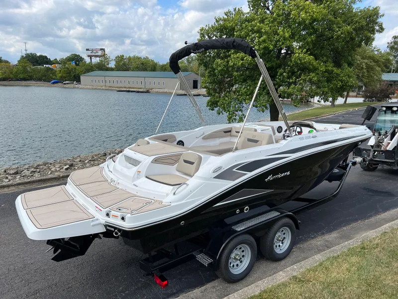 Slide: The Image of 2024 Hurricane SunDeck Sport 205 IO boat on trailer by a lake. - 2