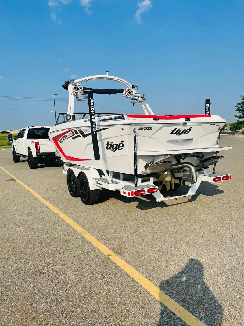 Slide: The Image of 2021 Tigé 22RZX boat on trailer, white and red, parked in lot. - 11
