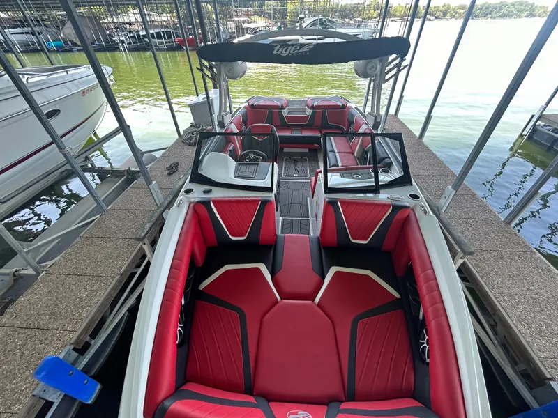 Slide: The Image of 2021 Tigé 22RZX boat with red and black interior docked at marina. - 18