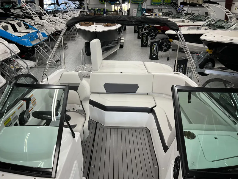 Slide: The Image of 2024 Hurricane SunDeck 187 IO boat interior with seating and steering wheel in showroom. - 13