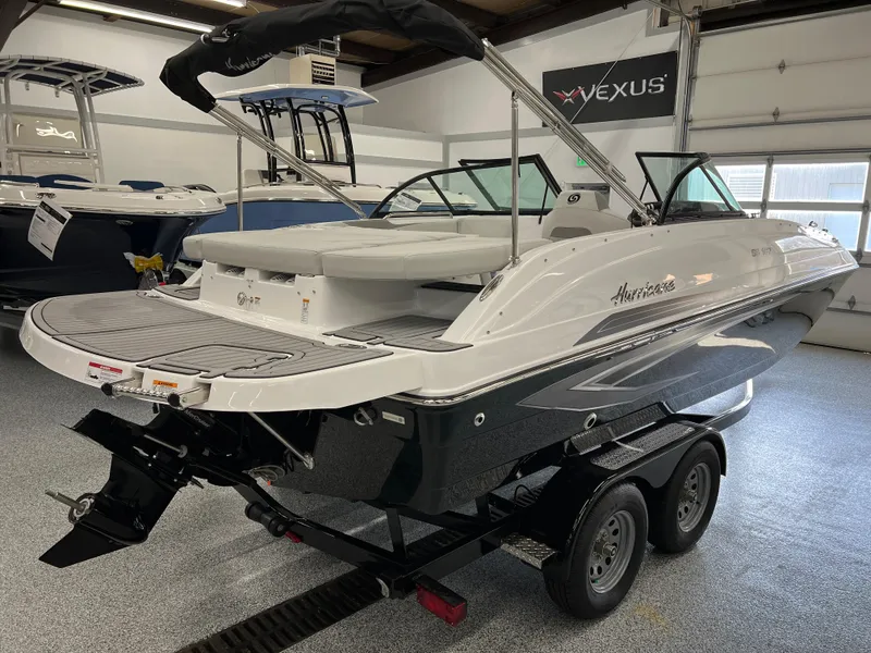 Slide: The Image of 2024 Hurricane SunDeck 187 IO boat on trailer in showroom, featuring sleek design and modern amenities. - 2